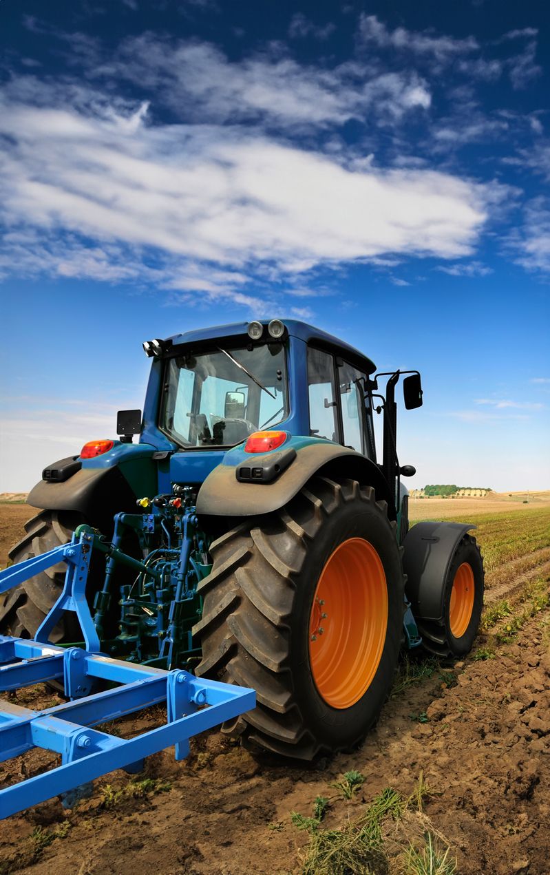 Ein Traktor pflügt ein Feld und hinterlässt frische Spuren im Boden.
