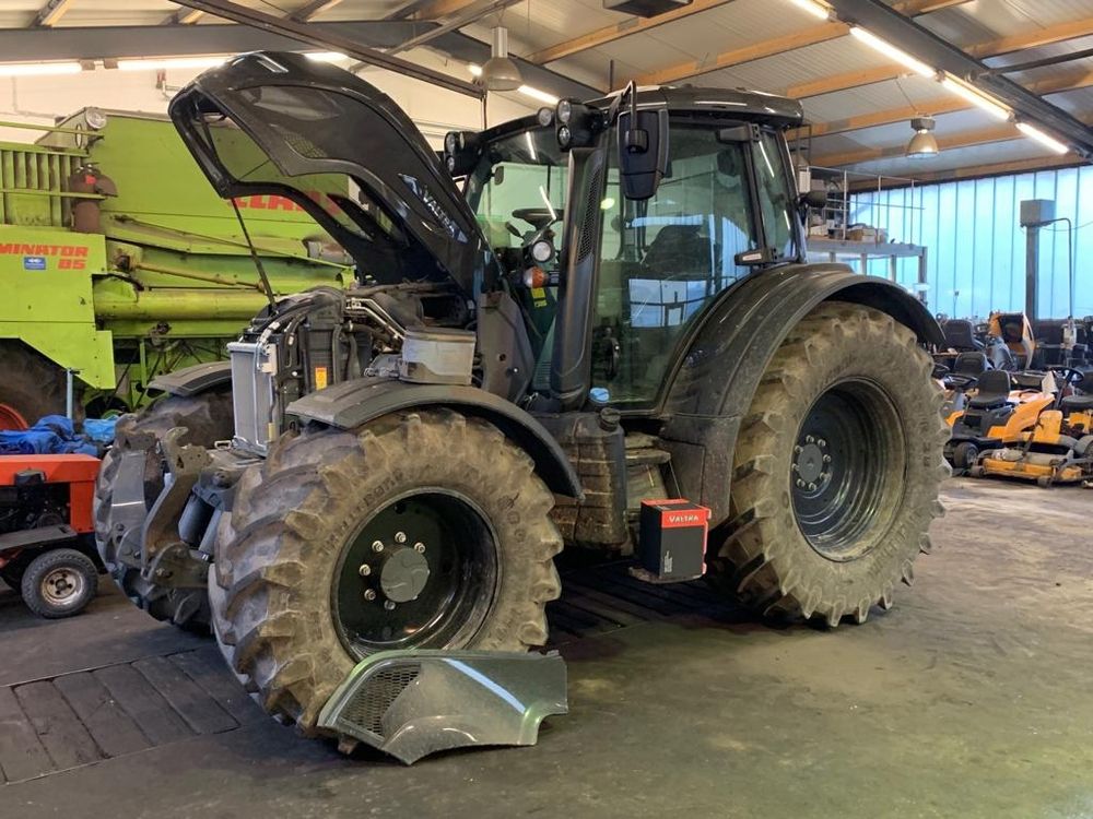 Ein Traktor mit markantem großen Vorder- und Hinterteil befindet sich in einer Lagerhalle